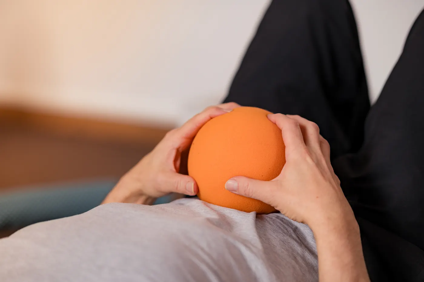 Mains tenant une balle sensorielle orange lors d'une séance de méthode MLC©